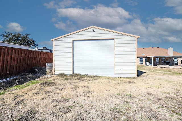 detached garage featuring driveway and fence