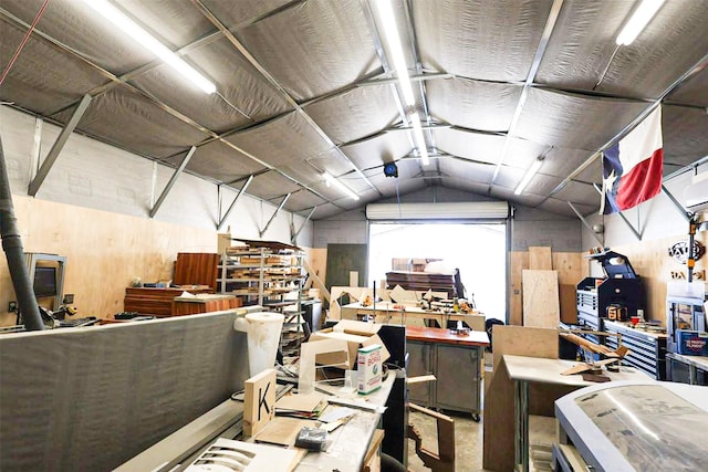 miscellaneous room featuring lofted ceiling, a workshop area, and wood walls