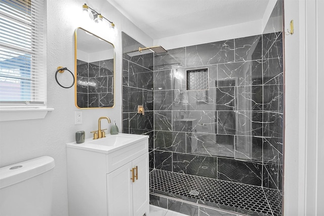 bathroom with tiled shower, vanity, and toilet