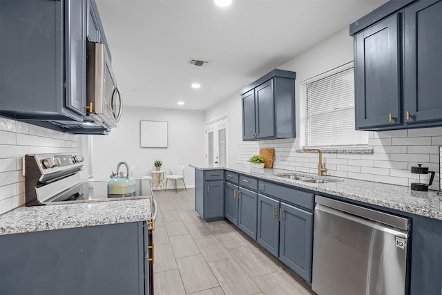 kitchen featuring sink, backsplash, blue cabinetry, and appliances with stainless steel finishes