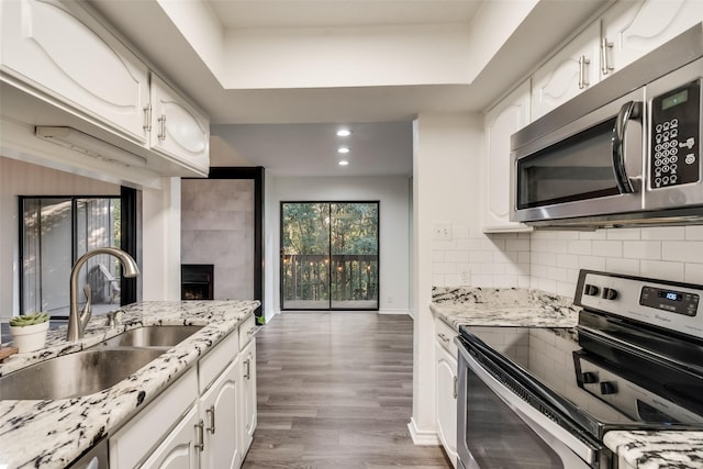 kitchen featuring sink, white cabinetry, light stone counters, appliances with stainless steel finishes, and decorative backsplash