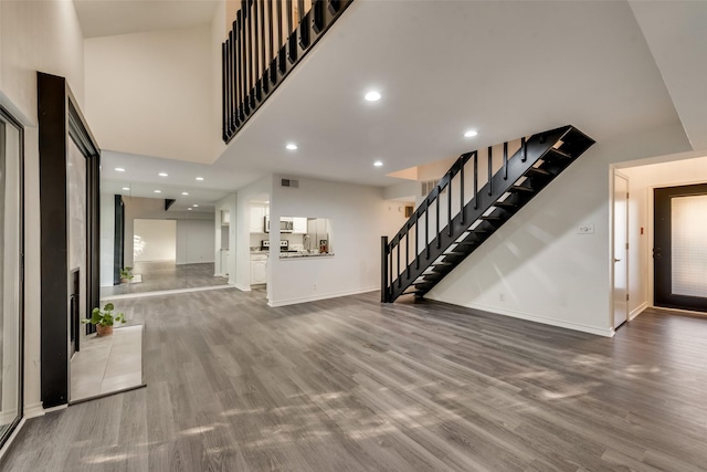 interior space with a towering ceiling and wood-type flooring