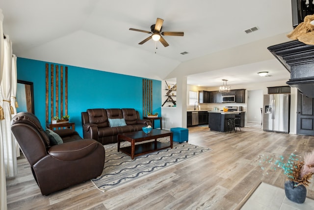 living room with sink, light hardwood / wood-style flooring, ceiling fan, and vaulted ceiling