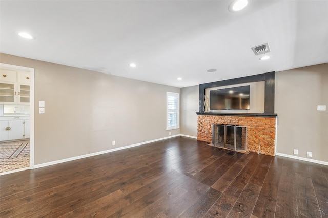 unfurnished living room featuring dark hardwood / wood-style flooring and a brick fireplace