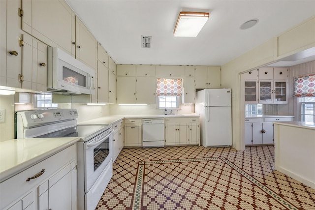 kitchen with white cabinetry, white appliances, and sink