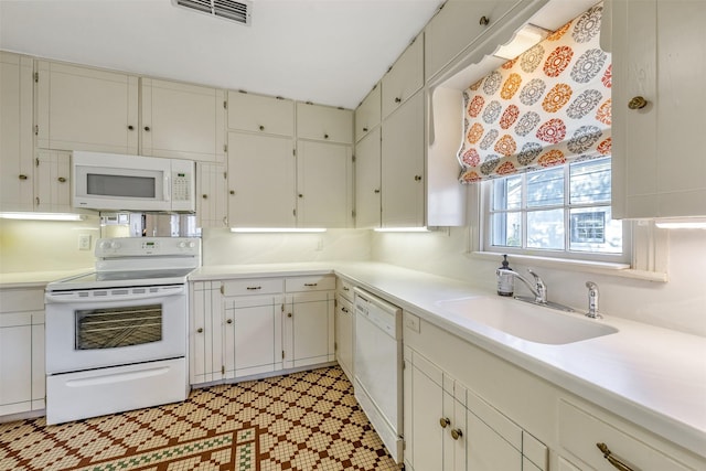 kitchen featuring sink, white cabinets, and white appliances