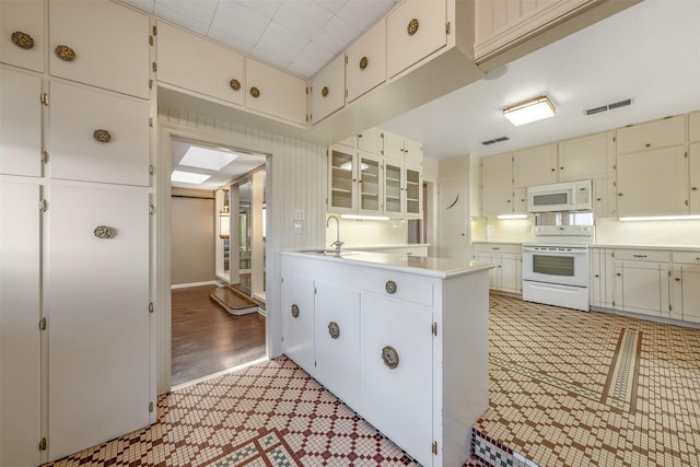 kitchen with white cabinetry, sink, white appliances, and kitchen peninsula