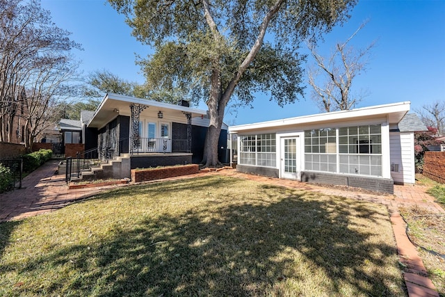 back of property with a sunroom and a lawn