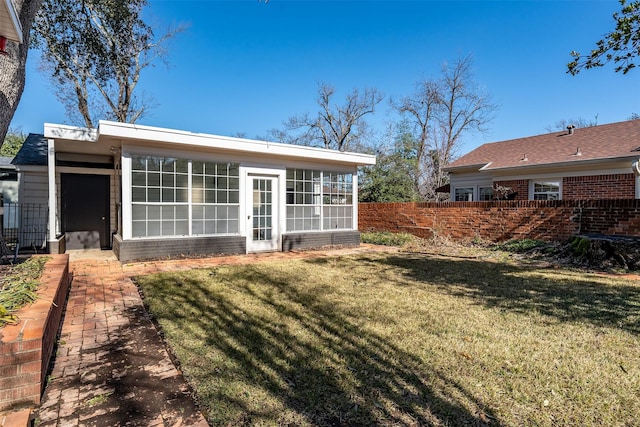 rear view of property with a sunroom and a lawn