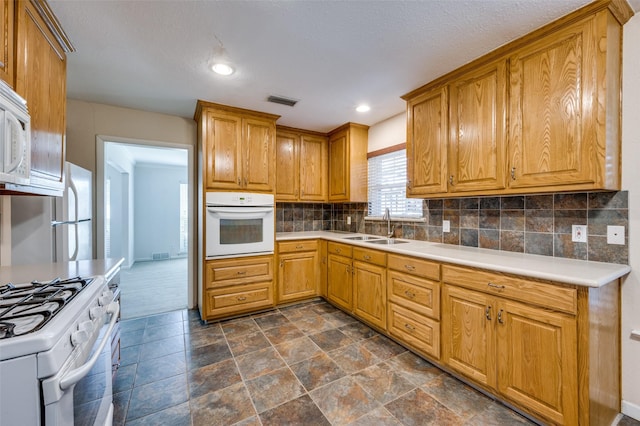 kitchen featuring sink, backsplash, and white appliances