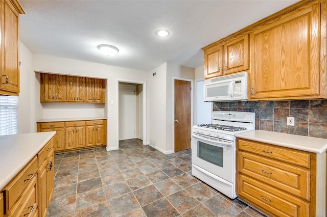 kitchen featuring a textured ceiling, backsplash, and white appliances