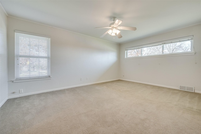 spare room featuring crown molding, ceiling fan, and light carpet