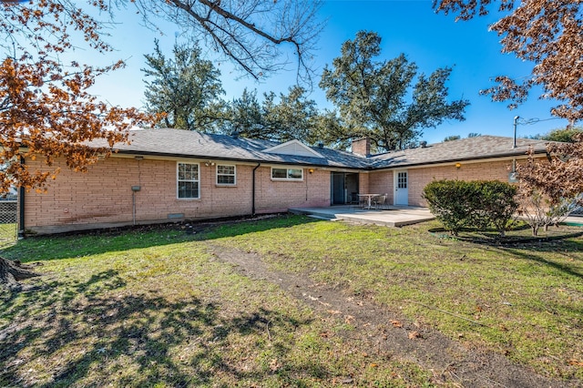 rear view of house featuring a lawn and a patio