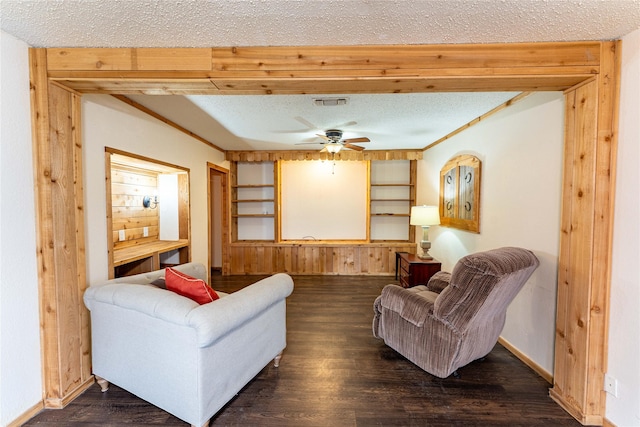 living room with dark hardwood / wood-style flooring, ceiling fan, a textured ceiling, and wood walls