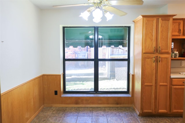 unfurnished dining area featuring wooden walls and ceiling fan