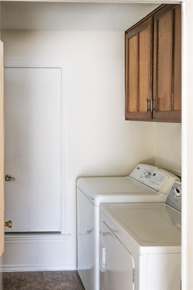 laundry room featuring separate washer and dryer, cabinets, and a textured ceiling