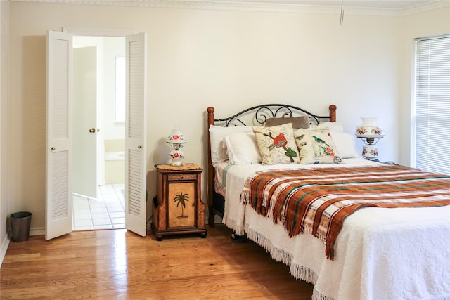 bedroom featuring crown molding, light hardwood / wood-style flooring, and ensuite bathroom