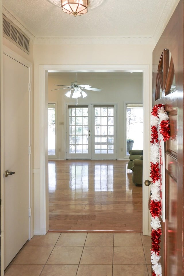 hallway with a wealth of natural light, a textured ceiling, and light tile patterned flooring