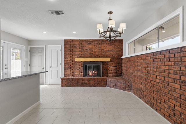 unfurnished living room with brick wall, light tile patterned flooring, a brick fireplace, and an inviting chandelier