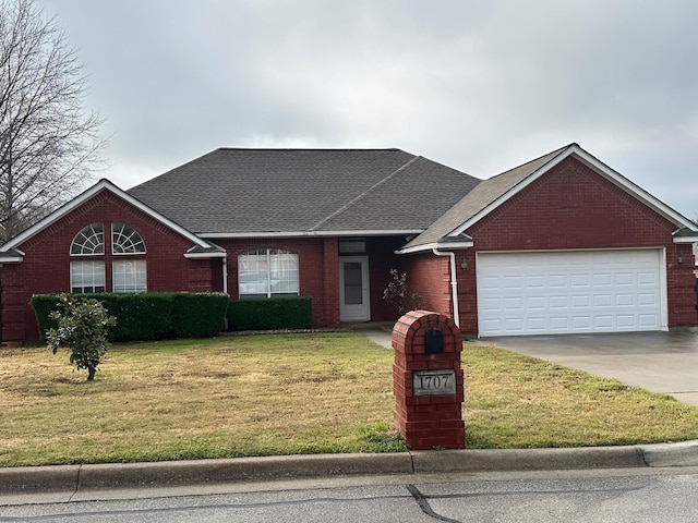 view of front of house featuring roof with shingles, brick siding, a front yard, a garage, and driveway