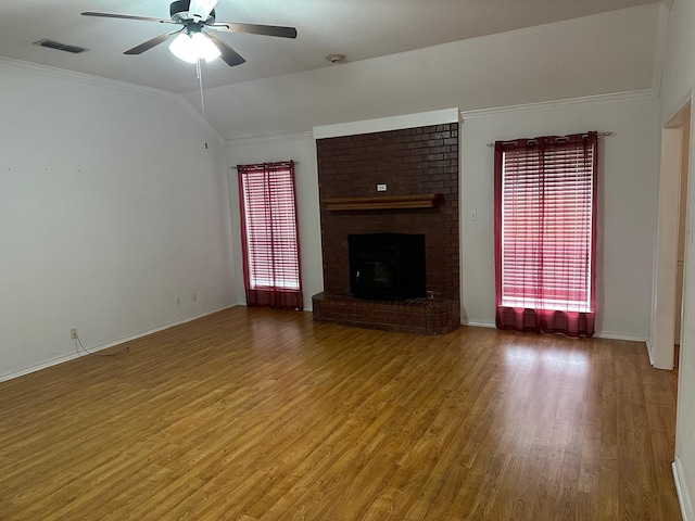 unfurnished living room with vaulted ceiling, wood-type flooring, ornamental molding, ceiling fan, and a brick fireplace