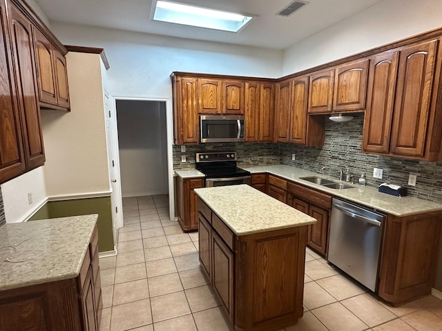 kitchen with sink, a skylight, appliances with stainless steel finishes, a kitchen island, and backsplash