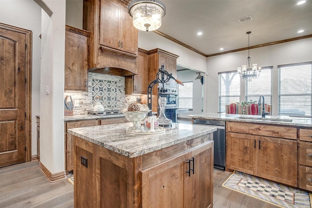 kitchen with appliances with stainless steel finishes, decorative light fixtures, sink, a center island, and light stone counters