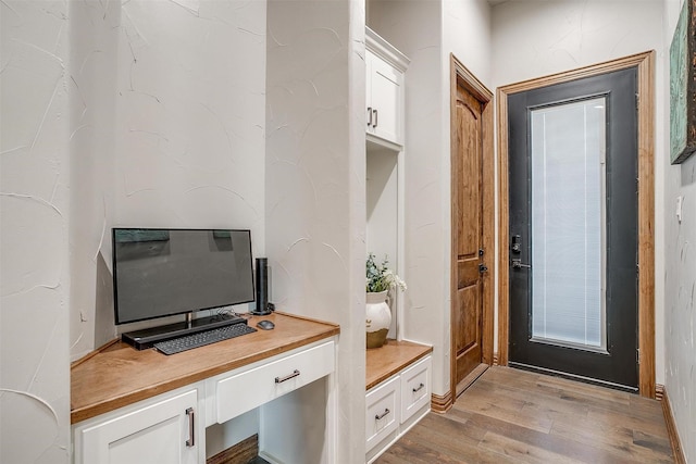 mudroom with built in desk and light hardwood / wood-style flooring