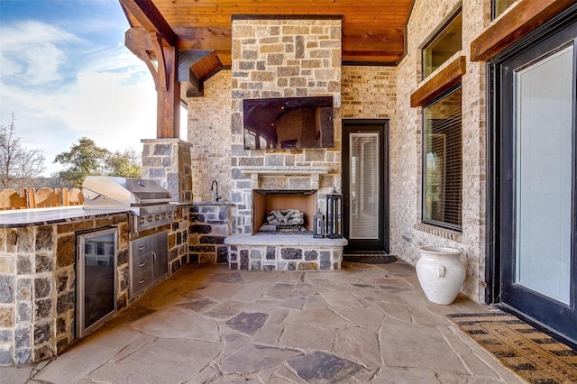 view of patio / terrace with an outdoor kitchen, a grill, and an outdoor stone fireplace