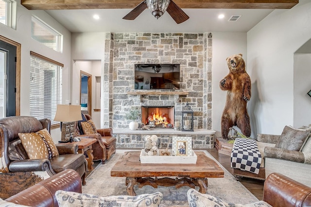 living room featuring a stone fireplace, a wealth of natural light, ceiling fan, and hardwood / wood-style flooring