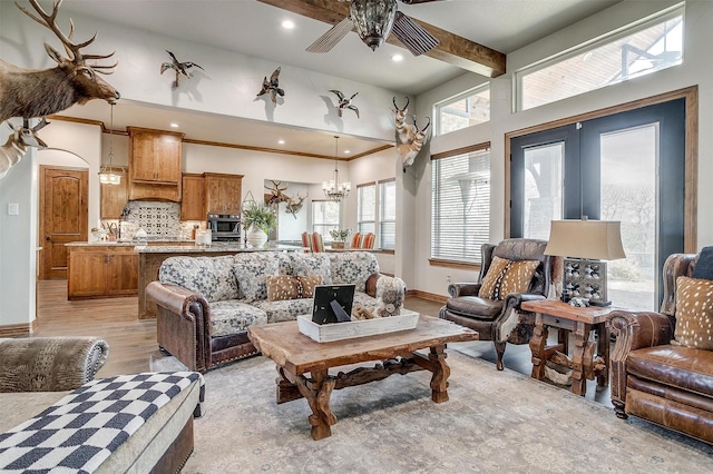 living room featuring beam ceiling, ceiling fan with notable chandelier, light hardwood / wood-style floors, and french doors