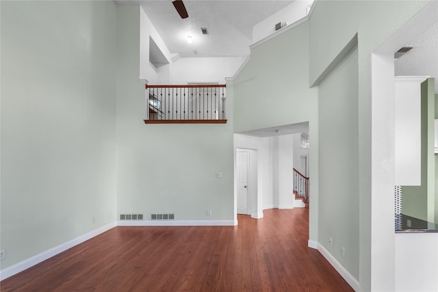 unfurnished living room with hardwood / wood-style flooring, ceiling fan, and a high ceiling