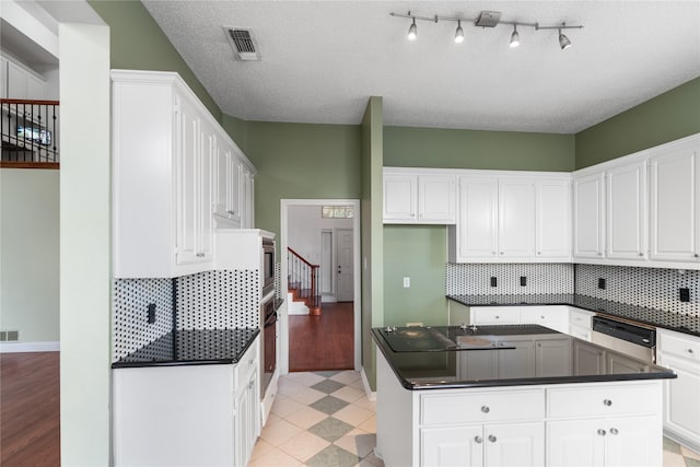 kitchen with stainless steel appliances, white cabinetry, tasteful backsplash, and a textured ceiling