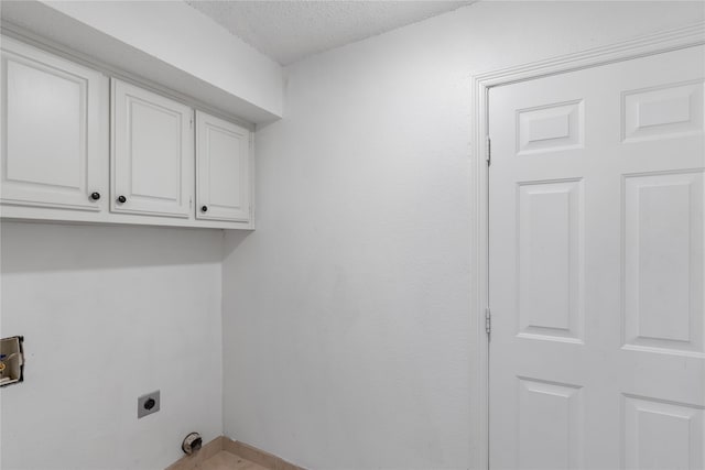 laundry room with electric dryer hookup, cabinets, and a textured ceiling