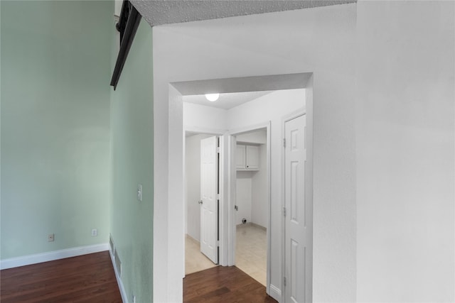 hall with hardwood / wood-style floors and a textured ceiling