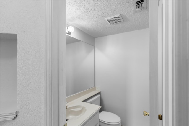 bathroom with vanity, toilet, and a textured ceiling