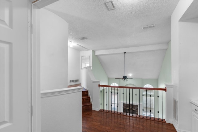 hall featuring vaulted ceiling, dark hardwood / wood-style floors, and a textured ceiling