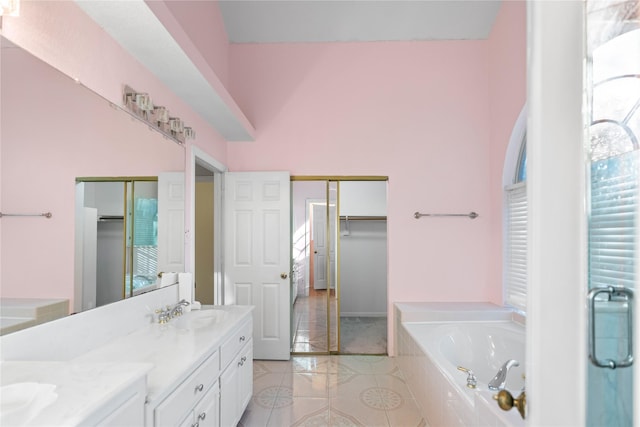 bathroom with vanity, tile patterned floors, tiled bath, and lofted ceiling