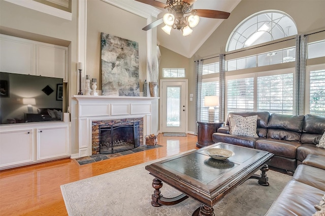 living room featuring light hardwood / wood-style flooring, a fireplace, high vaulted ceiling, and ceiling fan