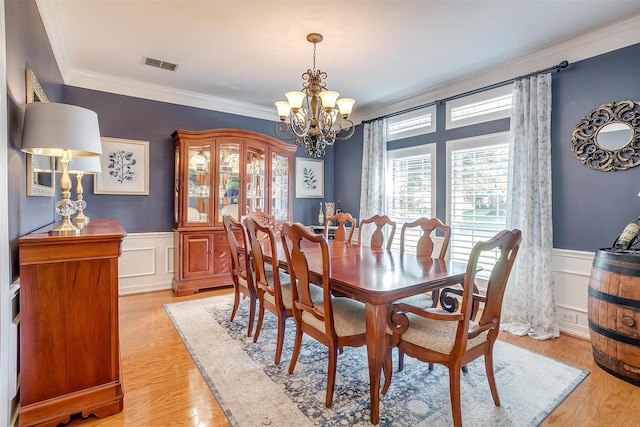 dining area featuring crown molding, an inviting chandelier, and light hardwood / wood-style floors