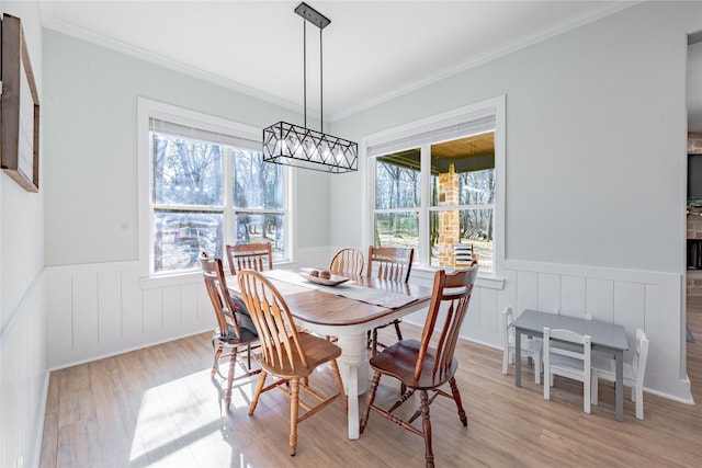 dining area featuring ornamental molding, light hardwood / wood-style flooring, and a notable chandelier