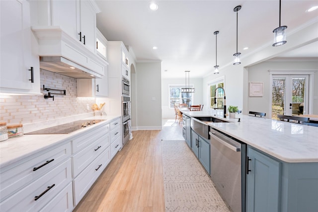 kitchen featuring hanging light fixtures, appliances with stainless steel finishes, white cabinets, and a spacious island