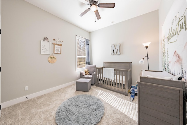 carpeted bedroom featuring ceiling fan and a crib