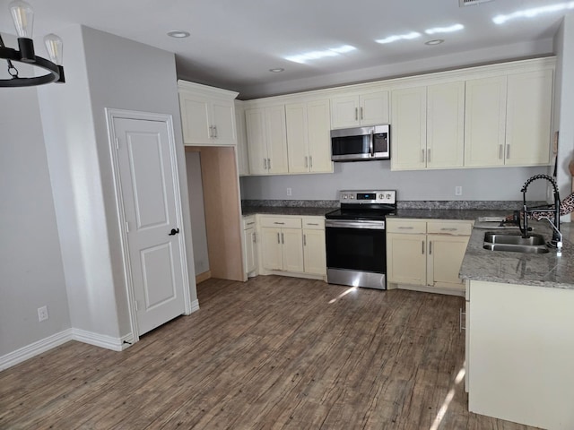 kitchen with light stone counters, stainless steel appliances, dark hardwood / wood-style flooring, and sink