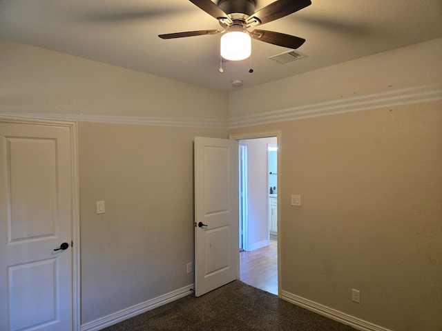 unfurnished room with dark colored carpet and ceiling fan