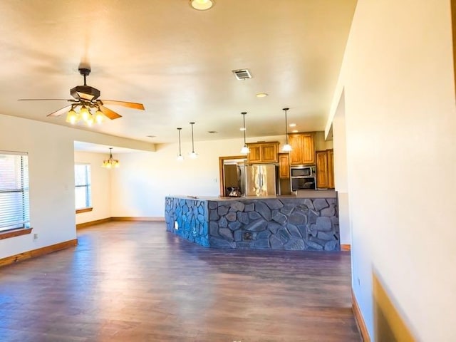 kitchen with dark wood-type flooring, ceiling fan with notable chandelier, stainless steel appliances, decorative light fixtures, and kitchen peninsula