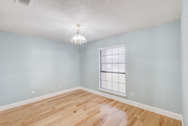 unfurnished room with wood-type flooring, a chandelier, and a textured ceiling