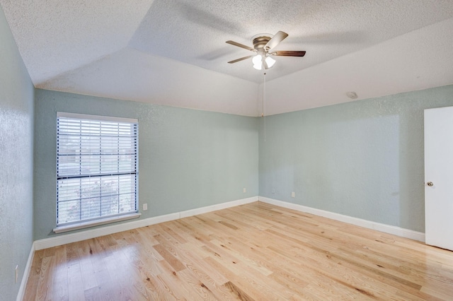 empty room featuring a textured ceiling, vaulted ceiling, light hardwood / wood-style floors, and ceiling fan