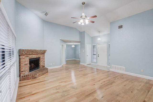 unfurnished living room with a brick fireplace, high vaulted ceiling, ceiling fan, and light wood-type flooring