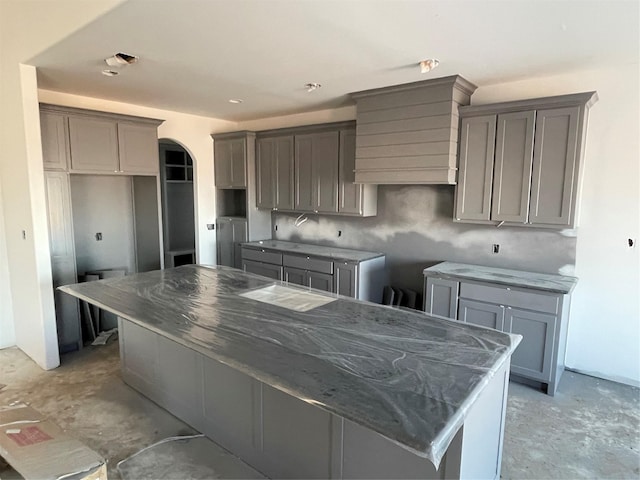 kitchen featuring gray cabinetry, dark stone counters, and a kitchen island